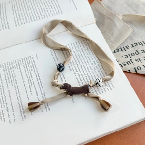 Vintage dachshund champagne silk scarf necklace with charm beads on an open book background