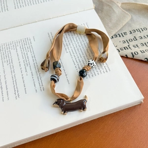 Detailed close-up of champagne silk scarf necklace with a brown dachshund dog pendant