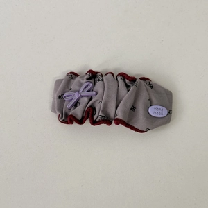 Detailed macro shot of floral fabric hair tie with handmade purple bow and plush edges