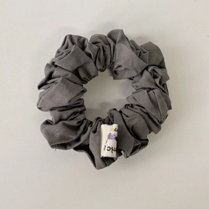 Detailed macro view of gray floral scrunchie texture with premium cotton fabric and brand tag