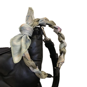 Foulard en soie à fleurs artistiques noué sur une poignée de sac en cuir noir