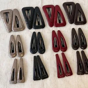 Faux leather geometric hair clips in various shapes and colors on beige fabric