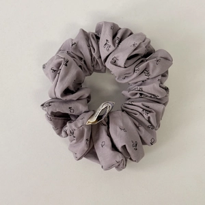 Detailed view of lavender floral print scrunchie with soft cotton texture and small white tag