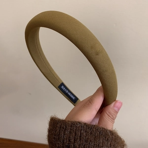 Detail view of khaki padded headband showing handmade label and premium twill fabric texture