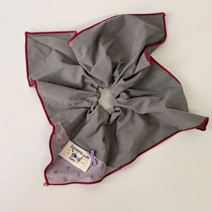 Detail of grey floral scrunchie with red contrast edging and 'Dynamic Life' woven label