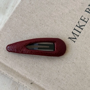 Close-up of deep red faux leather BB hair clip with textured crocodile pattern