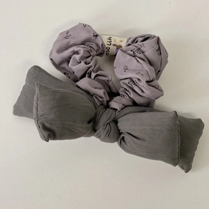 Detail of floral scrunchie and grey cotton bow hair ties showing fabric texture and label