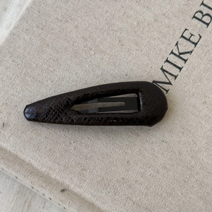 Macro shot of coffee brown faux leather drop-shaped hair clip with embossed texture
