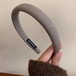 Close-up of handmade label on dark brown knitted sponge headband with ribbed texture