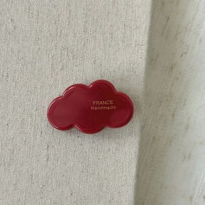 Detail of red cloud-shaped acetate hair clip with gold France Handmade lettering