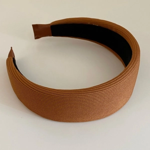Detail showing the ribbed knit fabric and thick padded design of the brown headband