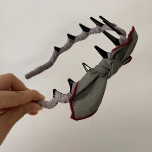 Detail of grey floral gothic headband with black spikes and dark red bow decoration