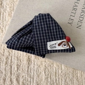 Detailed macro view of dark blue plaid fabric hair claw clip with cartoon label and red bead
