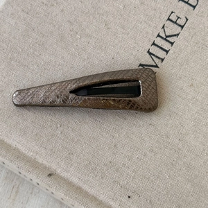 Detail of faux leather teardrop hair clip with snakeskin texture and bronze finish