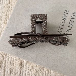 Detail of vintage brown plaid hair claw clip with a delicate faux leather bow decoration