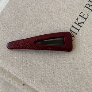 Detail view of burgundy faux leather triangle hair clip with lychee grain texture