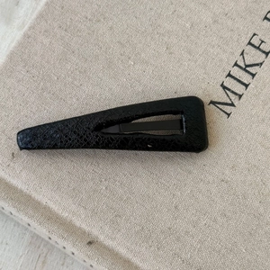 Detailed view of black teardrop BB hair clip with premium lychee faux leather texture