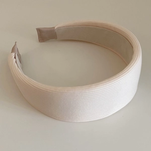 Detailed top view of a cream ribbed knit wide headband with a non-slip lining