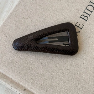 Detailed macro view of dark brown triangle hair clip with faux leather crocodile texture