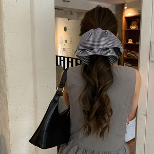 Elegant black and white gingham bow hair clip for women styled in a low ponytail