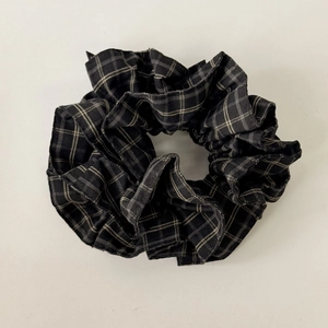 Detailed view of black and white checkered fabric scrunchie with soft pleated texture