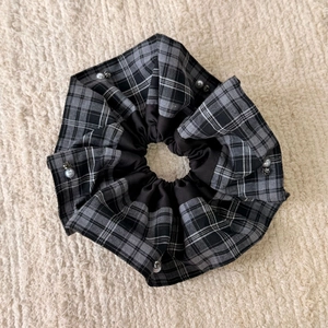 Close-up of plaid fabric scrunchie with pearl and rhinestone accents on soft plush background