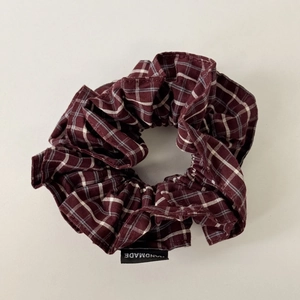 Detail view of double-layer plaid scrunchie with a handmade woven label in wine red