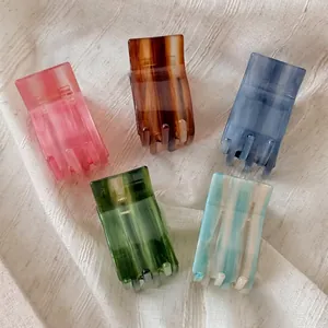 Five assorted gradient color rectangle acetate hair claws on beige linen fabric background
