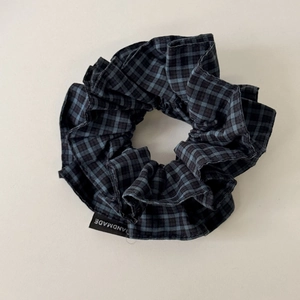 Detailed fabric texture of a navy blue plaid scrunchie with a handmade woven label tag