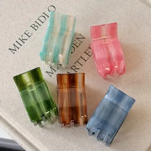 Five gradient acetate hair claws in pastel colors displayed on a stylish book cover