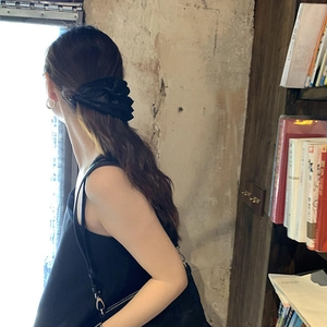 Elegant large black satin ribbon bow hair clip worn on long wavy hair for women