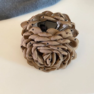 Detailed close-up of a French retro brown polka dot rose flower hair claw clip