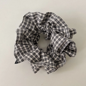 Close-up of black and white plaid cotton scrunchie with detailed woven texture and label