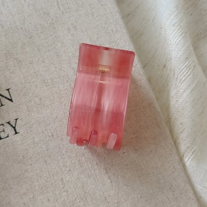 Detail of pink marble acetate hair claw clip on soft beige linen fabric background