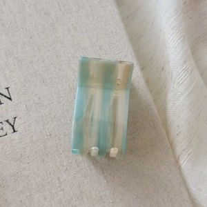 Detailed close-up of rectangular acetate hair claw with blue and beige marble texture