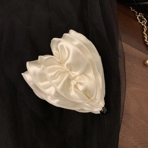 Detail of elegant cream satin heart-shaped hair clip with sophisticated pleated texture