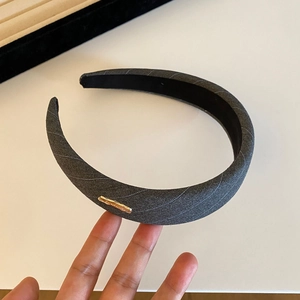 Detailed side view of dark grey striped fabric headband with rectangular gold metal accent