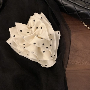 Macro detail of cream satin banana hair clip with retro black polka dots and pleated fabric