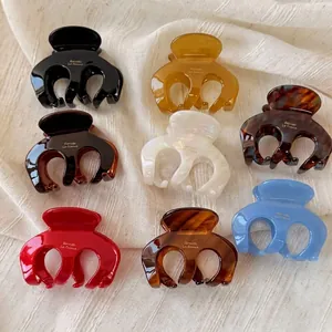 Octopus claw clips set in eight assorted acetate colors on a soft textured fabric background