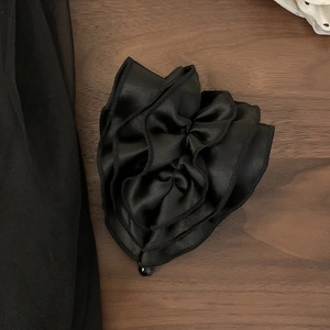 Detailed view of black satin hair claw with layered ruffles and a glossy center bead