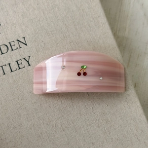 Detail of pink marble acetate hair claw clip with cherry rhinestone and crystal design