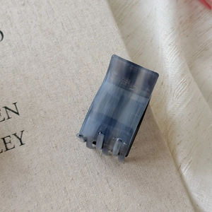 Detail of square acetate hair claw with smoky blue marble texture and multi-tooth design