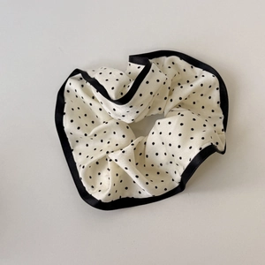 Detailed close-up of a satin polka dot scrunchie featuring elegant black lace trim borders