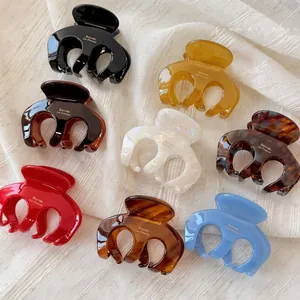 Close-up of 8 colorful acetate hair claws in glossy resin with gold lettering details