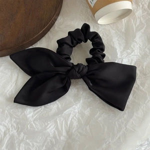 Close-up of black satin bow hair scrunchie with elegant silky texture and soft folds