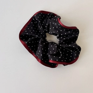 Elegant black polka dot scrunchie with burgundy satin trim on white background