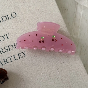 Detail of red rhinestone cherry motif on a light pink acetate hair claw clip