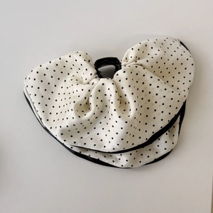 Close-up of white satin polka dot bow hair claw clip with black stitched edge detailing