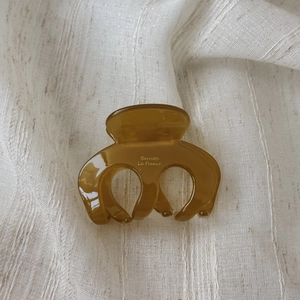 Close-up of amber acetate hair claw clip with Barrette La France text on linen fabric