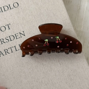 Detailed view of dark brown cherry claw clip with red rhinestones on a vintage book